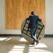Man carrying Lifetime round folding table folded flat, showing compact portable design with locking frame and steel legs