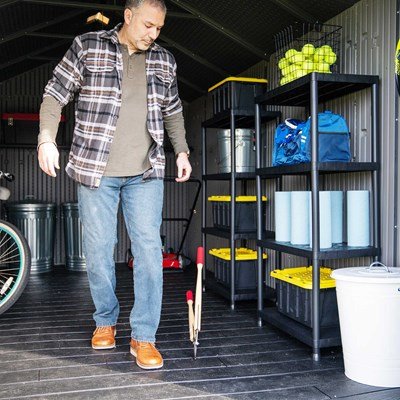 Man standing inside the Lifetime 8x15 ft. storage shed next to organized shelving and storage totes.