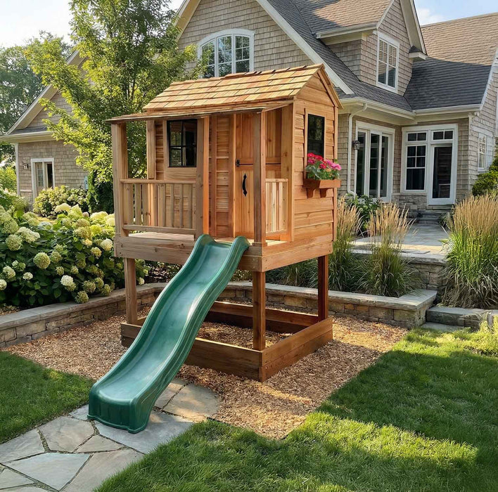 Front view of the Little Cedar Playhouse with green wave slide near a shingle-style home
