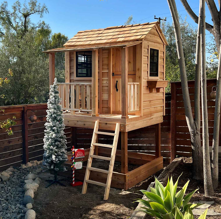 Little Cedar Playhouse 6x6 with holiday decorations in a backyard setting with rock garden