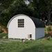 Rear view of the Little Cottage Co. 10x12 Round Roof Coop in white with a small chicken door and ramp, surrounded by chickens in the yard.