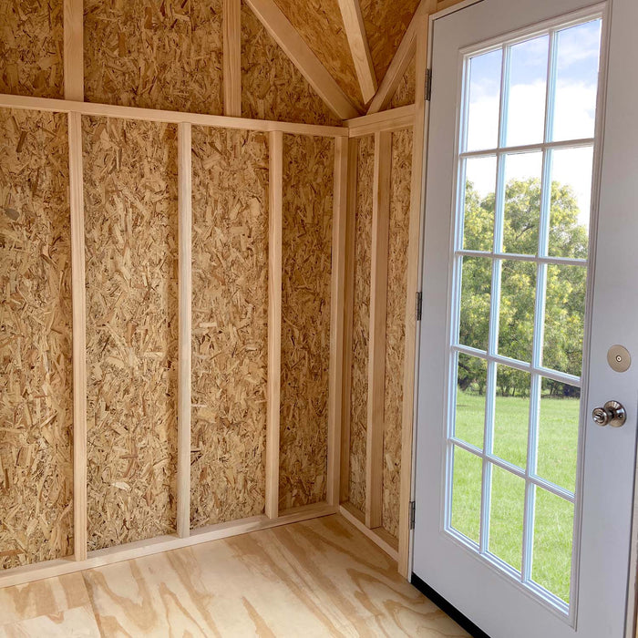 Interior of Little Cottage Co. Grand Portico Mansion showing glass French door, natural wood walls, and bright daylight from windows