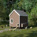 Side view of Little Cottage Co. 6x8 Chicken Coop in brown with white trim, showing hens roaming around and a wooden ramp leading to the entry door.