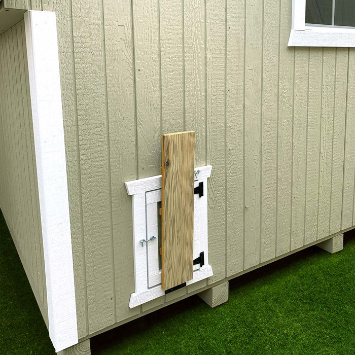 Side view of the Little Cottage Co. Round Roof Coop showing the small chicken door with a ramp beneath a large window on beige siding.
