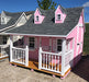 Side view angle of the Pennfield Cottage Playhouse by Little Cottage Company, showcasing its delightful pink and white paint scheme.