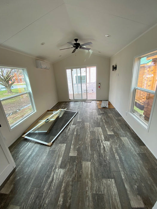 Spacious living area inside the Champion Home without Loft by Oasis Tiny Estates, featuring multiple large windows and modern flooring.