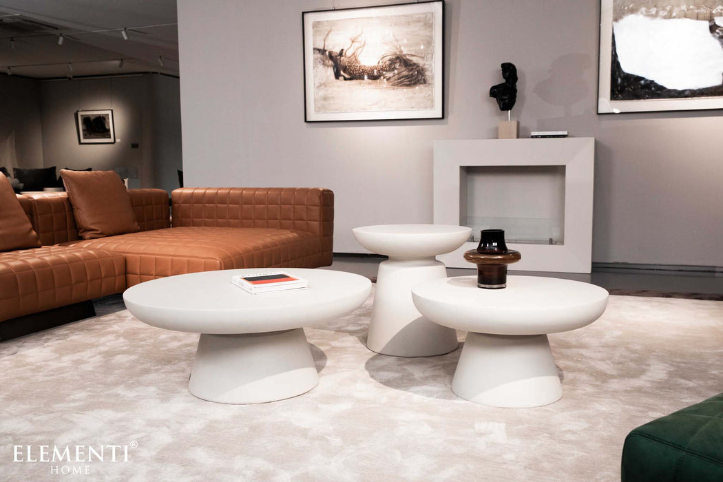 Elementi Kylix Series small and medium coffee tables in cream white in a stylish living room setting with a brown leather sofa.