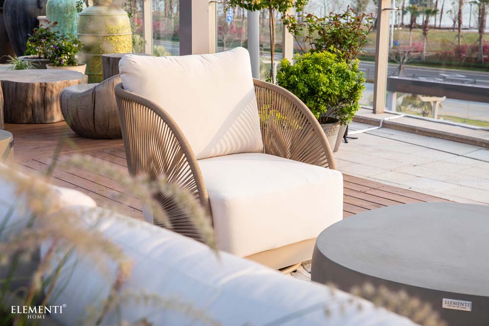 Elementi Outdoor Furnitures Malibu Collection chair placed on a stylish terrace, blending woven textures with natural greenery in a serene setting.
