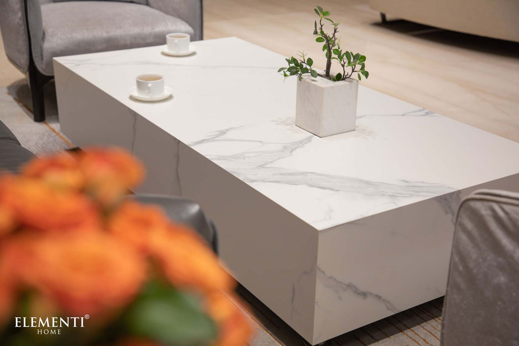 Elementi Marble Coffee Table in Bianco White in a living room setting, styled with tea cups and a potted plant for an inviting atmosphere.