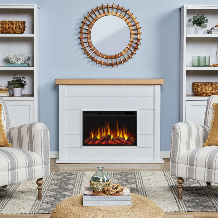 Real Flame Marshall Slim Electric Fireplace in white shiplap mantel in bright coastal living room with rattan mirror, striped armchairs, and glowing orange flames