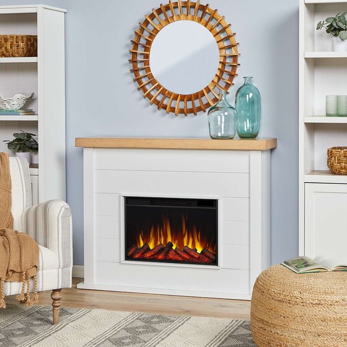 Real Flame Marshall Slim Electric Fireplace in white shiplap mantel styled in cozy living room with round rattan mirror, teal vases, and striped armchair
