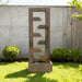 Minimalist cascade outdoor water fountain with four flowing tiers, styled in modern yard with concrete wall and shrubs