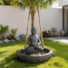 Modern backyard Buddha bowl water fountain with smooth black finish, floating flowers, and minimalist garden setting.