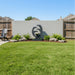 Wide backyard view highlighting Eclipse modern outdoor fountain against stucco wall with green lawn and decorative rocks.