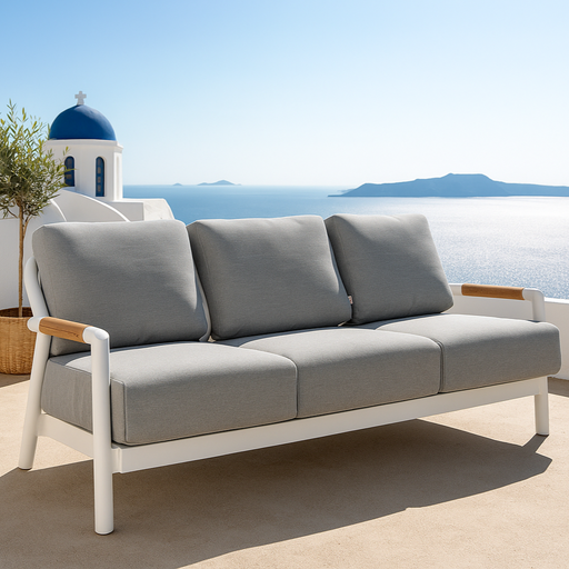 Elementi Outdoor Furnitures Santorini Collection three-seater sofa with grey cushions overlooking the ocean and white Santorini architecture.