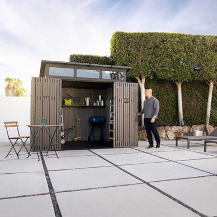 Man approaching the Lifetime Modern Shed with open doors, patio table and chairs nearby.