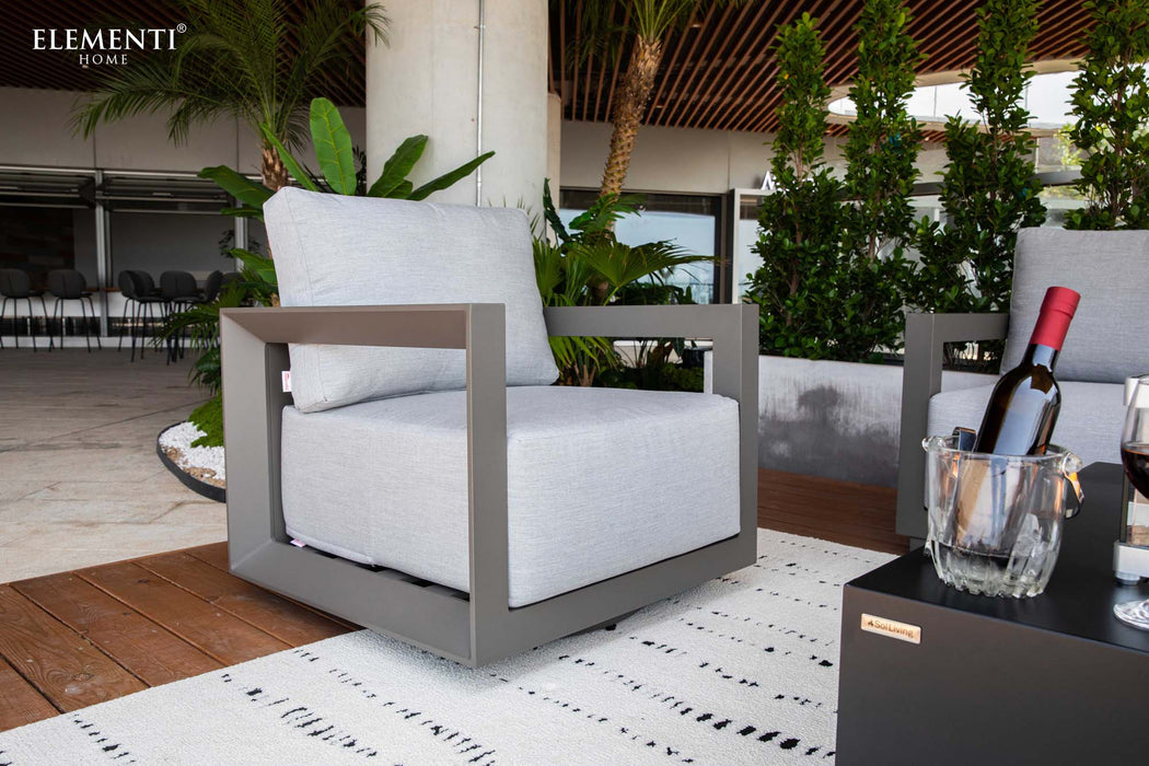 An elegant Elementi Newport Collection armchair with a fire pit table, featuring a bottle of wine, perfect for outdoor relaxation.