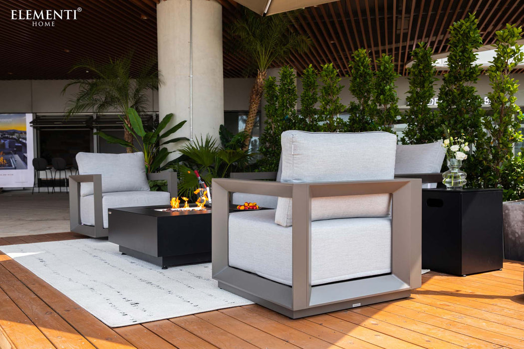 A luxurious Newport Collection outdoor lounge set by Elementi, featuring armchairs, a sofa, and a central fire pit.