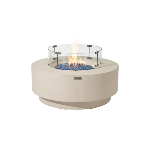 Studio shot of the Elementi Plus Nimes round concrete fire pit table, frosted cream white, lit flame with glass guard on white background