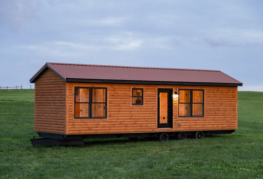 Wildfire Cabin on wheels parked in a grassy field at dusk.