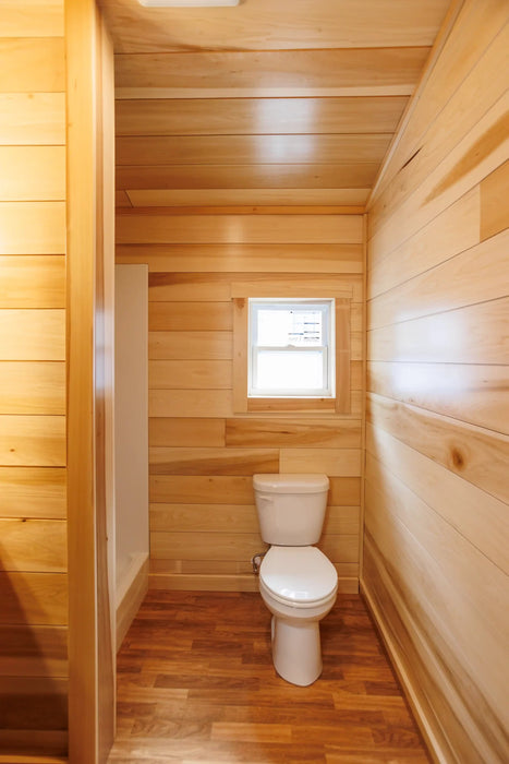 Bathroom inside the Oasis Tiny Estates Firestack Cabin, with toilet and a shower space on the side. 