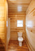 Bathroom inside the Oasis Tiny Estates Firestack Cabin, with toilet and a shower space on the side. 