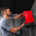 Man placing a red toolbox inside the Lifetime Classic 8x5 Storage Shed.