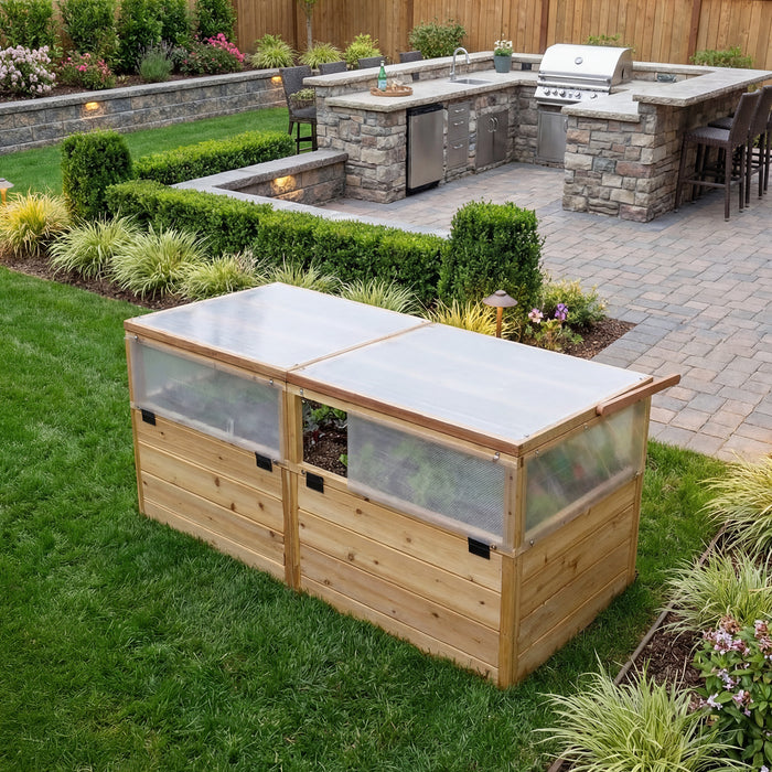 Greenhouse with Garden in a Box 6x3 on a manicured lawn, western red cedar frame with clear panel walls and hinged lids near a stone kitchen