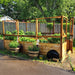 8x12 Garden in a Box with Deer Fence in a backyard, western red cedar frame full of leafy vegetables with barrel planters of herbs alongside