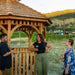 Friends with wine gathered at the Outdoor Living Today 10' Bayside Panelized Octagon Gazebo, cedar shake roof and railings beside a vineyard