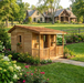 Single-story configuration of the Cozy Cabin Playhouse Kit nestled in a landscaped garden bed with hydrangeas and roses