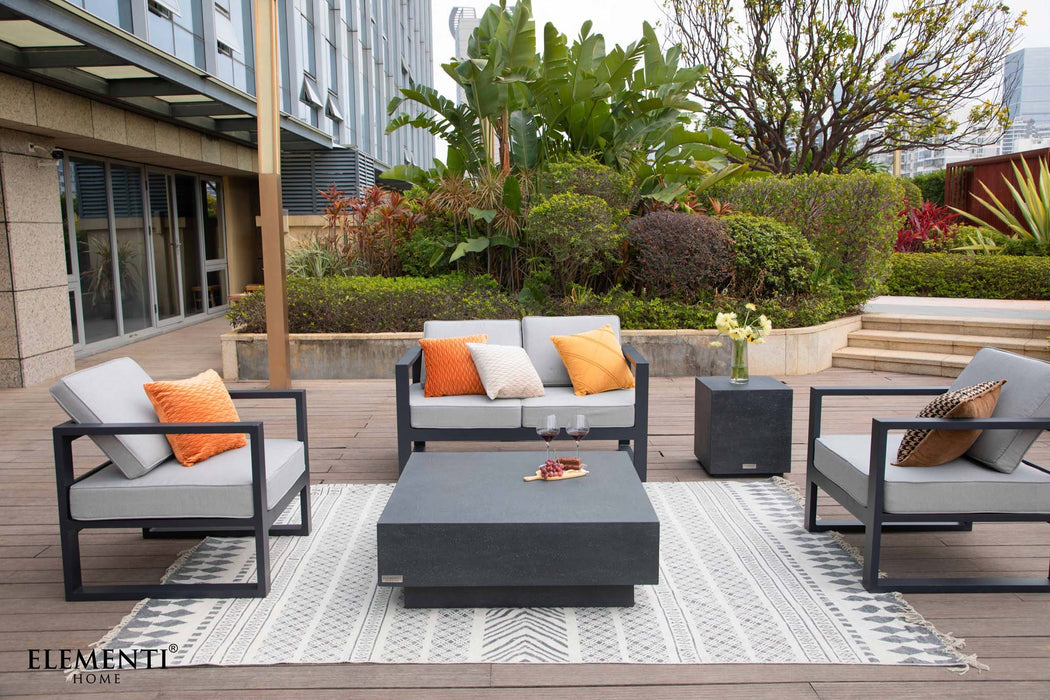 A spacious patio lounge setup featuring the Elementi Tevere Series Square Coffee Table in Slate Black, accompanied by modern seating.