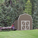 Handy Home Hudson storage shed in a forested area with vintage farm equipment nearby.