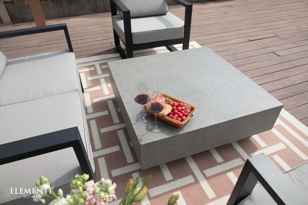 A relaxed outdoor scene with wine and snacks set on the Elementi Tevere Series Square Coffee Table in Space Grey.