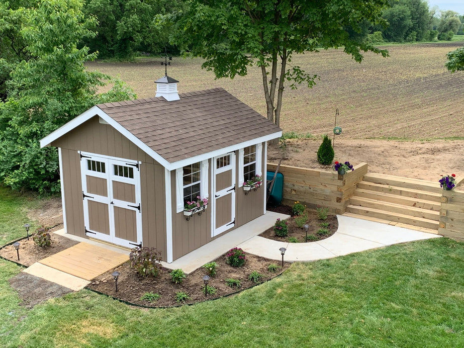 outdoor ez fit riverside shed painted brown on a concrete foundation with ramp and sidewalk