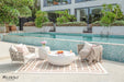 Elegant outdoor patio setup featuring the Elementi Ikaria Coffee Table Cream White with a vase of flowers, fruits, and drinks by a luxurious pool.