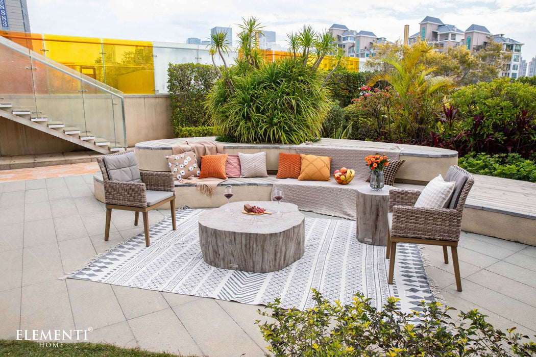 Patio setting with the Elementi Daintree drift wood large coffee table, featuring wicker chairs and vibrant cushions.