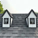 Close-up of two dormer windows on the Little Cottage Co. Pennfield Cottage Playhouse, showing white trim, black framing, and gray shingle roofing detail.