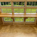 Interior of Petite Greenhouse by Little Cottage Co. featuring wood shelf and large multi-pane windows letting in natural light for growing plants