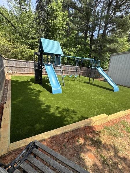 Lifetime Big Stuff Deluxe playset installed on artificial turf in a customer's backyard, wide angle view.