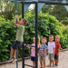 Boy climbing the Lifetime playset's monkey bar pole while four kids wait in line to take their turn.