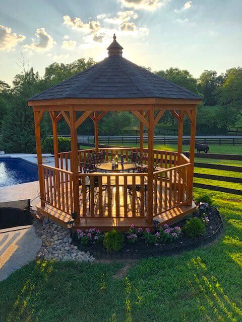 Amish 8 Foot Wood Gazebo-In-A-Box with Floor beside a pool & a garden