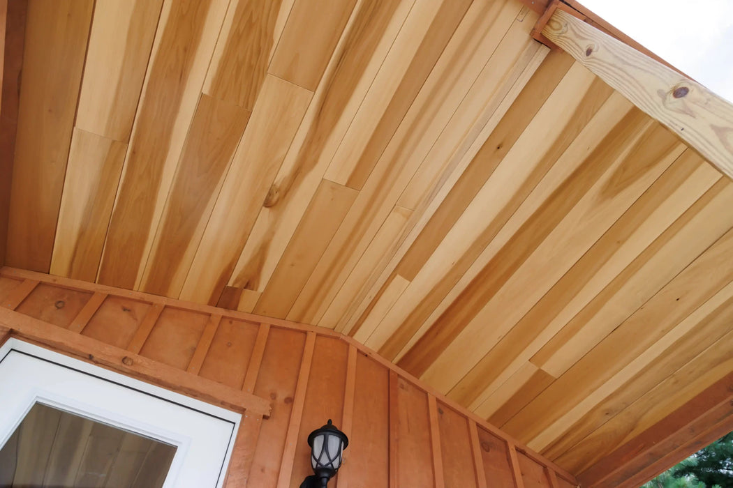 lose-up of the porch ceiling of the Oasis Tiny Estates Firestack Cabin, featuring the wooden beams, door, and front porch light. 