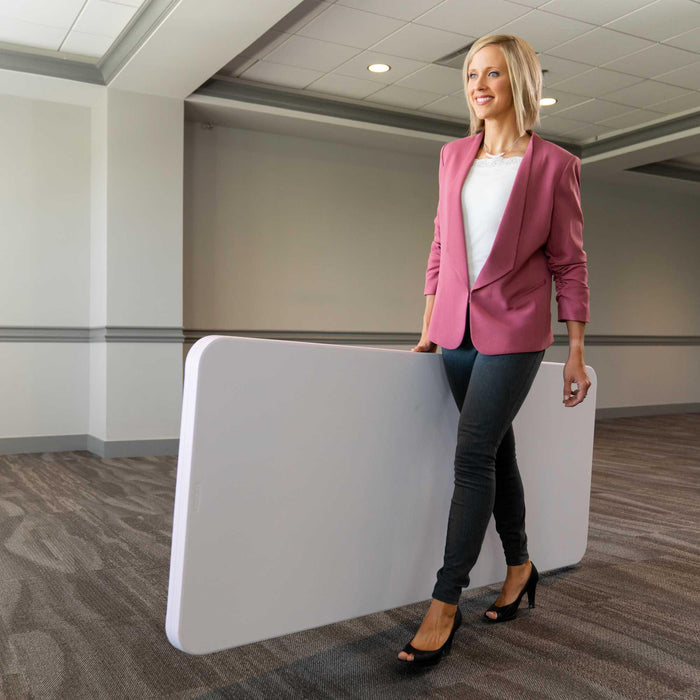 Woman carrying Lifetime 4 Pack 6-Foot Rectangle Folding Table in folded position for easy transport