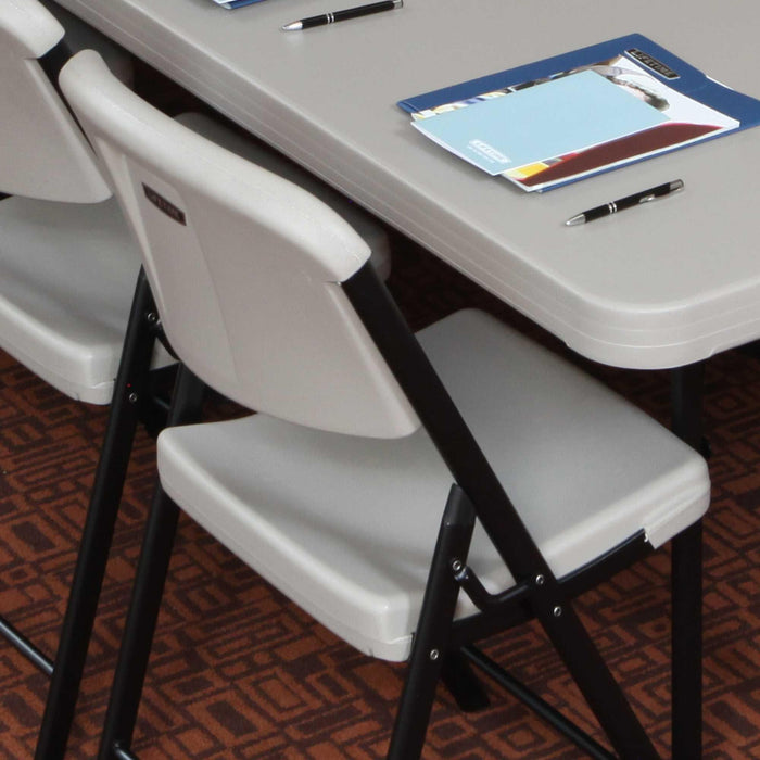 Lifetime 4-Pack Classic Folding Chair in putty tucked under folding table showing compact storage design