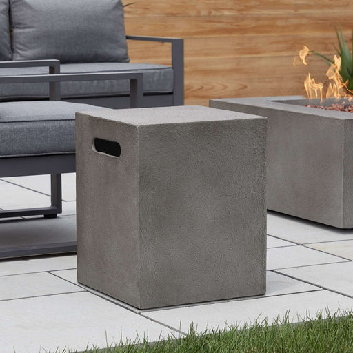 Stylish outdoor scene featuring the Real Flame Baltic Propane Tank Cover placed beside a fire pit and seating area.