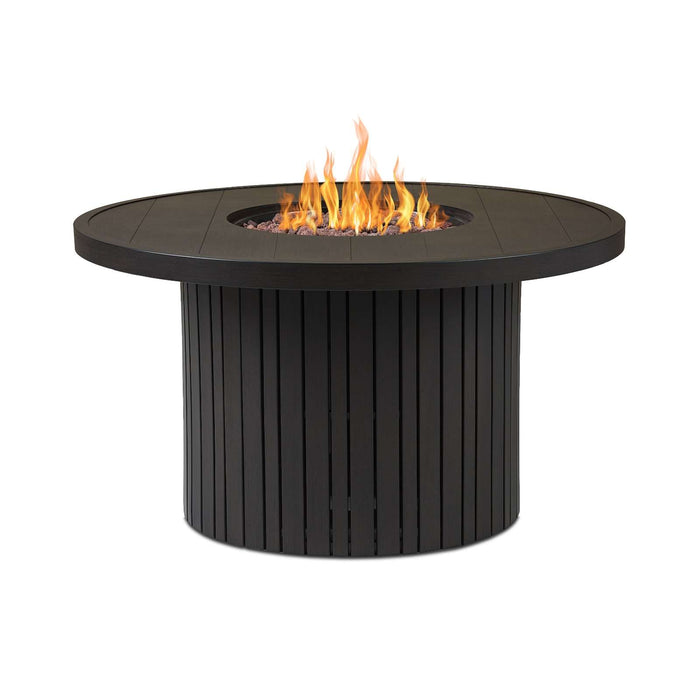 Real Flame Calvin 44" Round Propane Fire Pit Table in black with tall open flames and lava rocks, fluted cylindrical aluminum base, on a clean white background