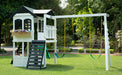 Reign Two Story Playhouse with swing set in a playground