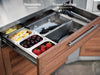 Removable stainless steel garnish trays in the NewAge Classic Bar Cabinet's top drawer, filled with lemons, cherries, and strawberries.