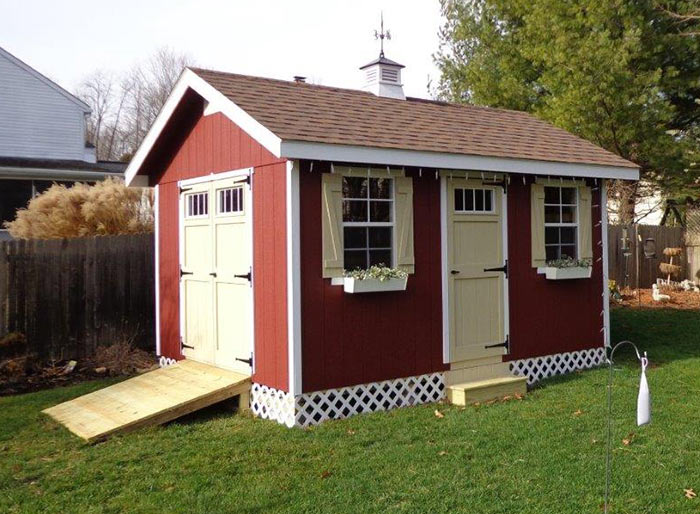 Riverside outdoor storage shed with roof shingles and cupola painted red.